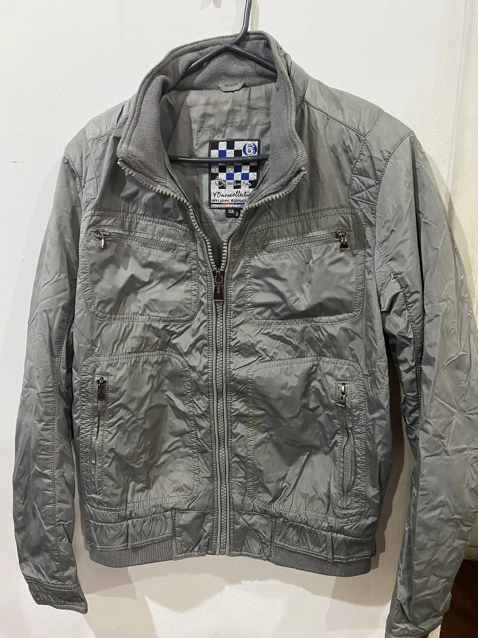 Campera bomber gris con cierre y múltiples bolsillos. Ideal para un look casual y urbano.