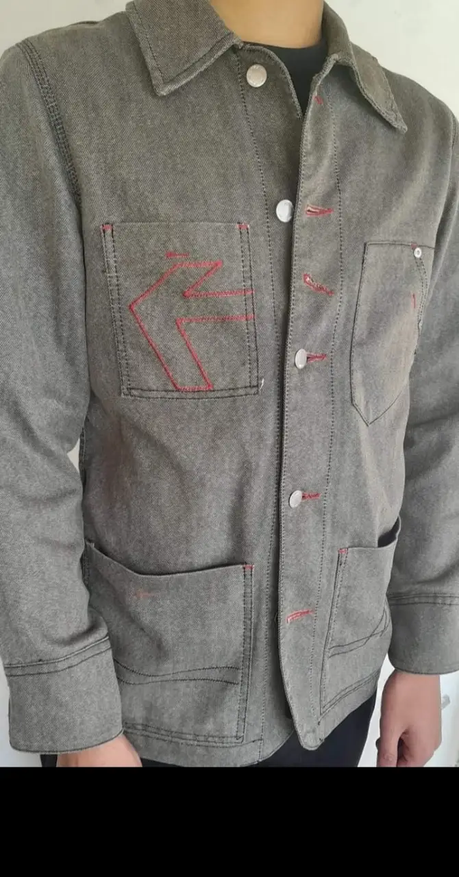 Campera de jean gris con detalles en rojo. Posee bolsillos delanteros y botones plateados. Ideal para un look casual y canchero.