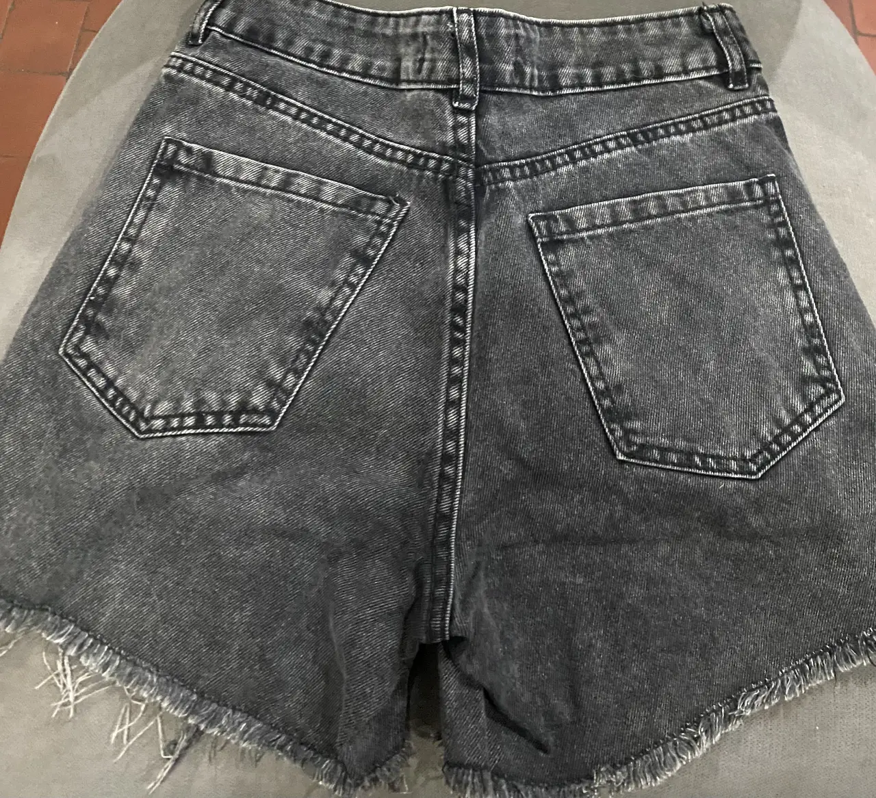 Short de jean negro con roturas y flecos en el borde. Tiro alto, ideal para un look casual y canchero.
