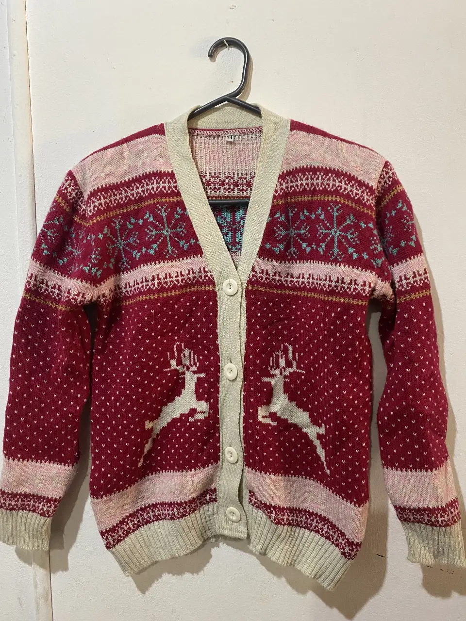 Cardigan navideño de punto, con diseño de renos y copos de nieve. Ideal para un look retro y festivo.