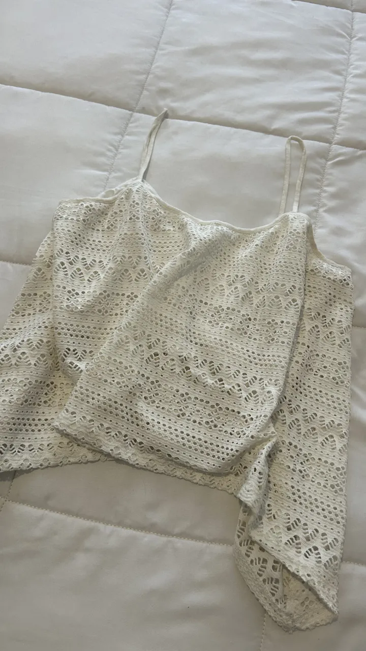 Top blanco de breteles finos con detalles de tejido calado en toda la prenda. Posee un forro interior de tela lisa.