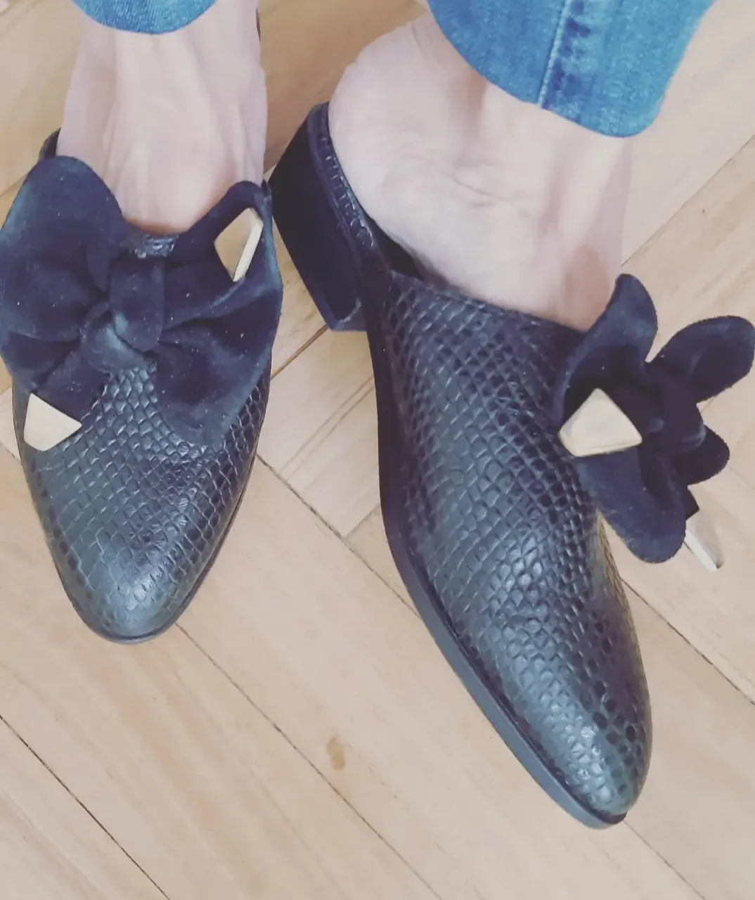 Zuecos de mujer negros con diseño de reptil y moño de terciopelo. Ideales para un look elegante y sofisticado.