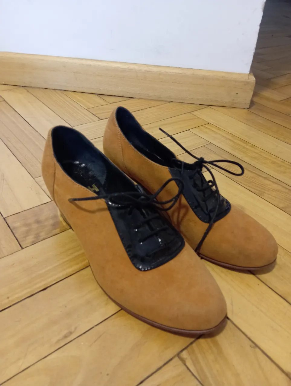 Zapatos de mujer estilo Oxford, con puntera y detalles en charol negro y cuerpo en gamuza marrón. Taco cuadrado.