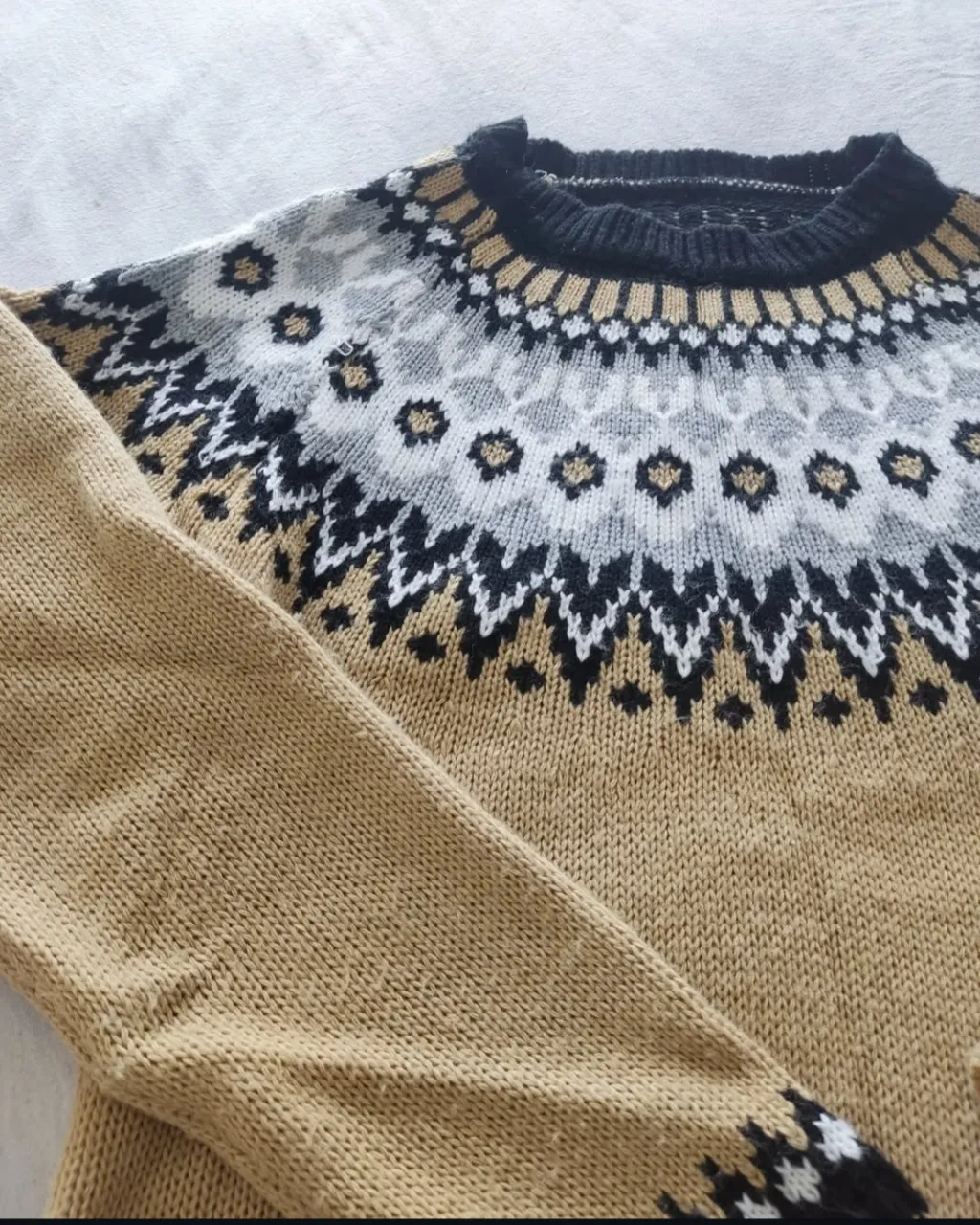 Sweater de lana con diseño nórdico en tonos amarillo, negro, blanco y gris. Cuello redondo y puños con detalles a juego. Ideal para un look casual y abrigado.