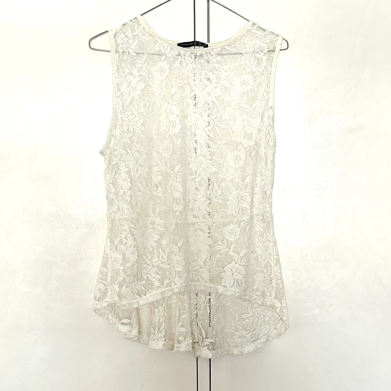 Blusa de encaje blanca, sin mangas, con diseño floral. Ideal para un look elegante y fresco.