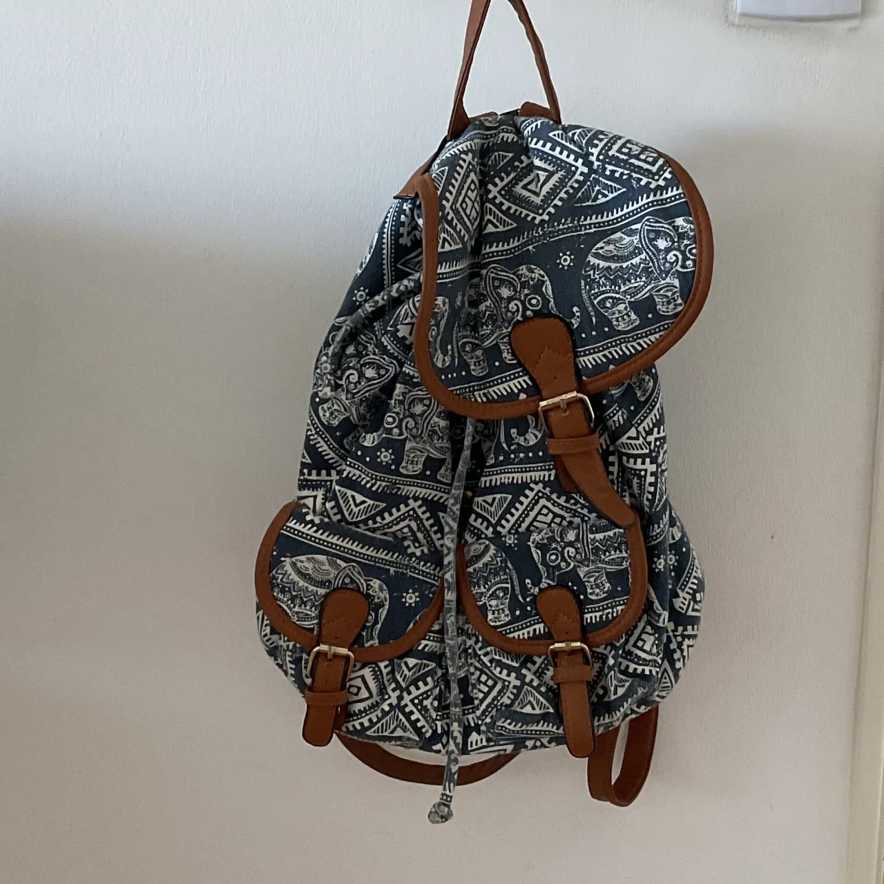 Mochila de tela con estampa de elefantes y detalles en cuero sintético. Ideal para el día a día, viajes cortos o para llevar tus esenciales con estilo. Posee múltiples bolsillos y cierres.