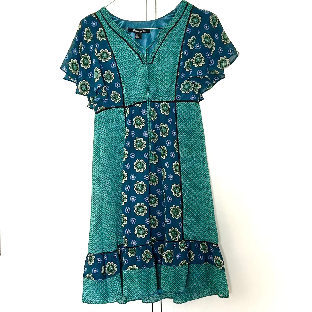 Vestido midi de Forever 21, con estampado floral en tonos turquesa y verde. Diseño con mangas cortas con volados, detalles en negro y cierre frontal. Ideal para un look fresco y femenino.