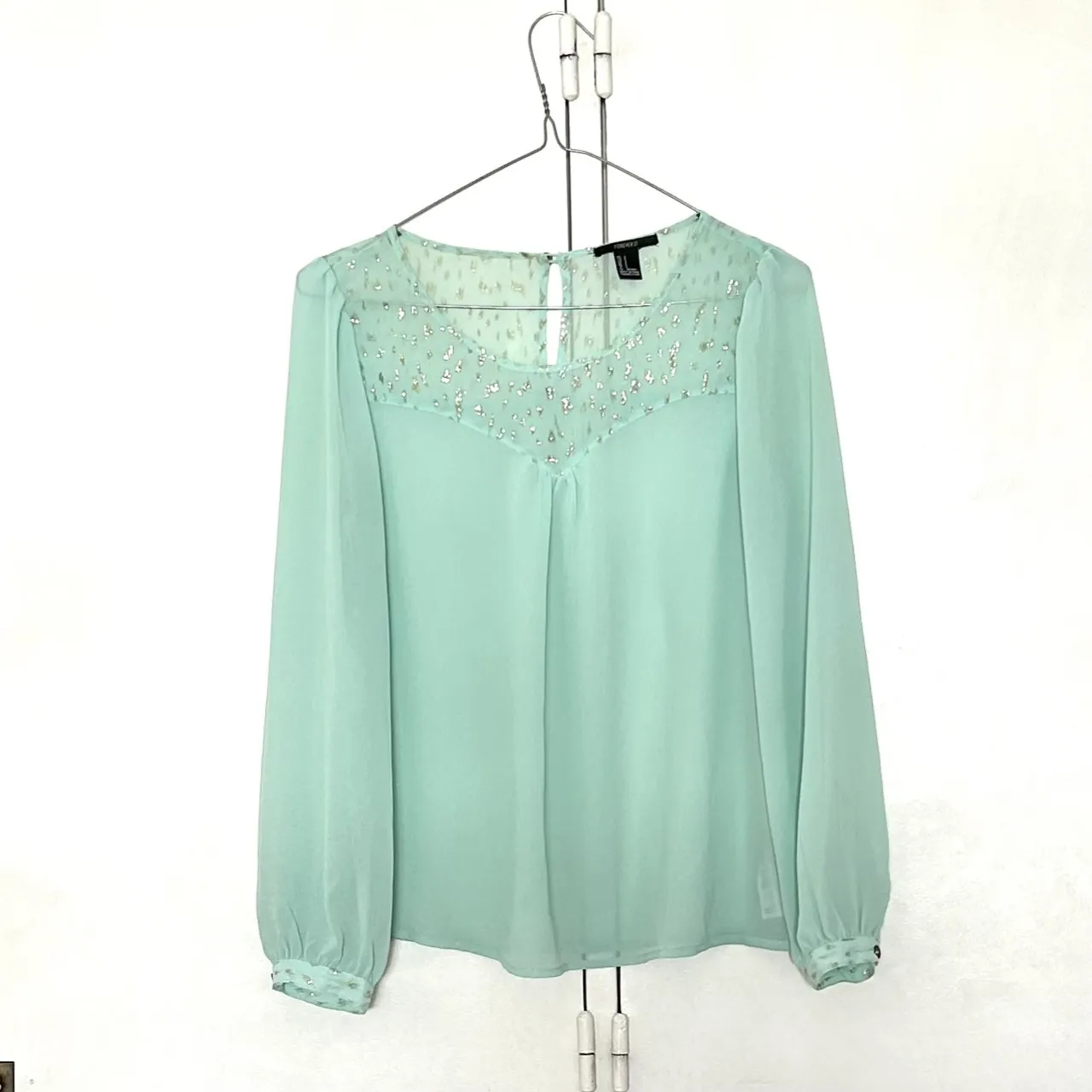 Blusa de manga larga color verde agua con detalles de pedrería en el frente. Ideal para un look elegante y fresco.