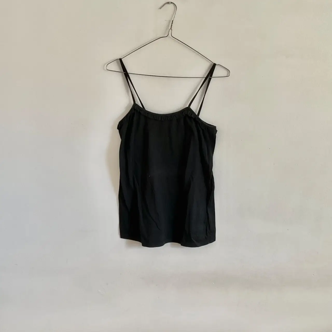 Musculosa negra con tiras finas, ideal para combinar con cualquier outfit casual. Perfecta para el verano.
