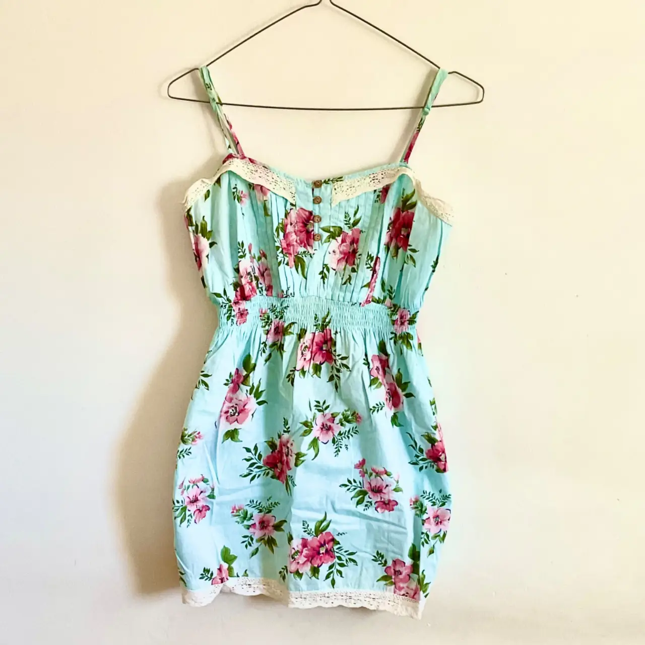 Vestido mini de verano, con estampado floral en tonos rosa y celeste. Diseño con tirantes finos, cintura elastizada y detalles de encaje. Ideal para un look fresco y romántico.