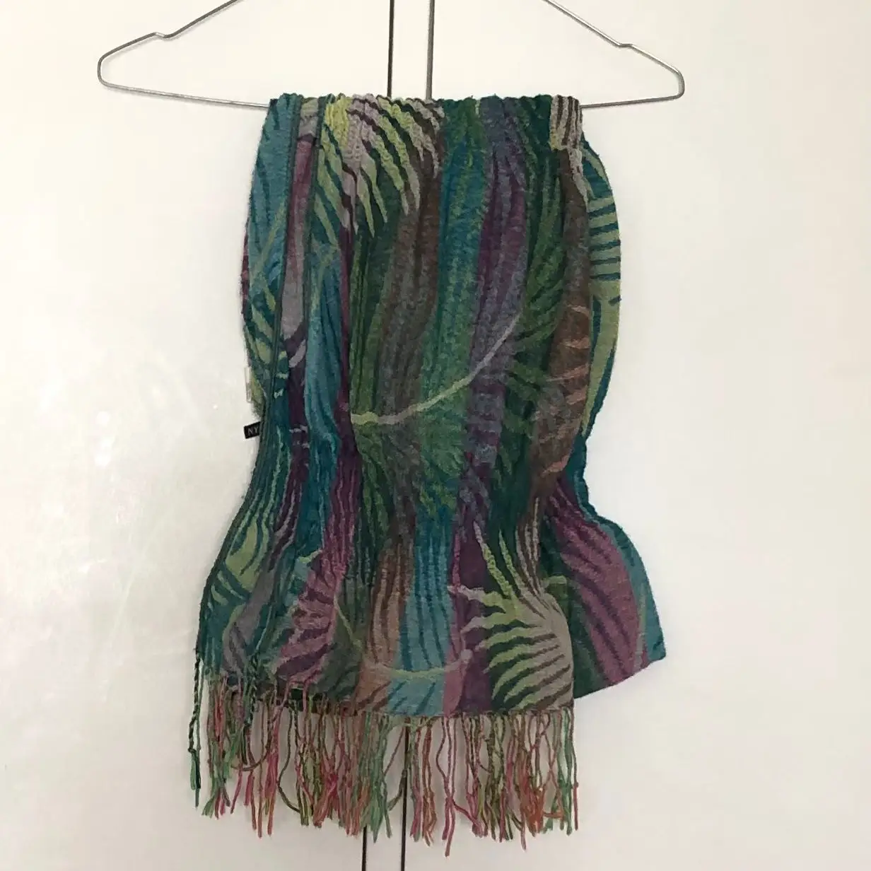 Bufanda de diseño con estampado de hojas en tonos verdes, azules y morados. Ideal para agregar un toque de color y estilo a cualquier atuendo.