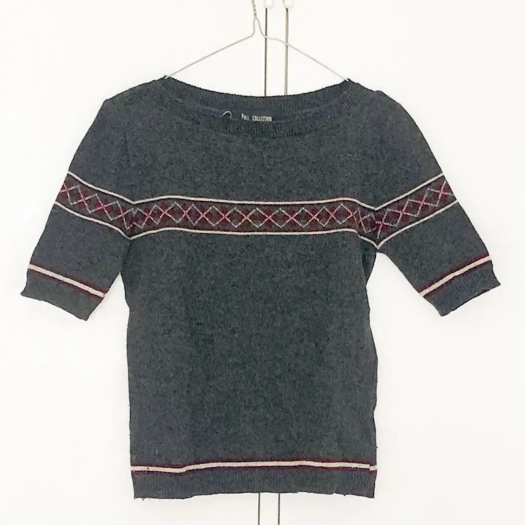 Sweater gris con detalles en rojo y blanco. Diseño con rombos en el pecho y mangas cortas. Ideal para un look casual y abrigado.