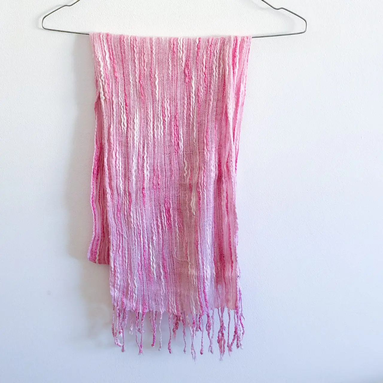Bufanda de tela rosa y blanca con flecos en los extremos. Ideal para complementar cualquier look.