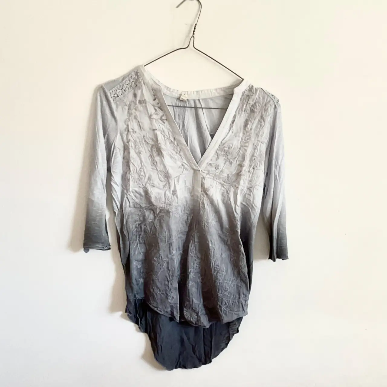Blusa de mujer con cuello en V y mangas 3/4. Diseño con degradado de color gris y detalles bordados. Ideal para un look casual y elegante.