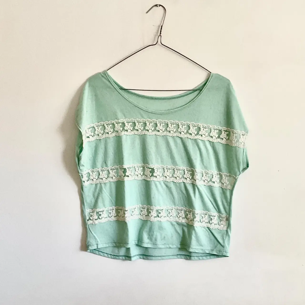 Remera de manga corta para mujer, de color verde claro con detalles de encaje blanco. Ideal para un look casual y fresco.