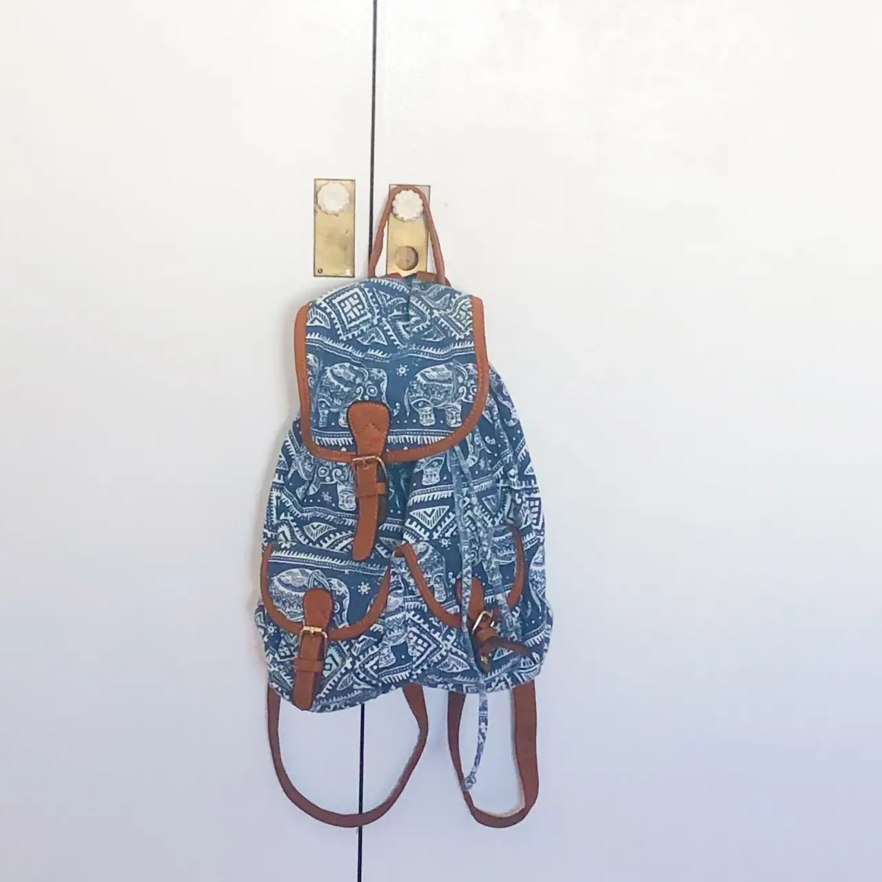 Mochila azul con estampado de elefantes y detalles en marrón. Ideal para llevar tus cosas con estilo y comodidad.