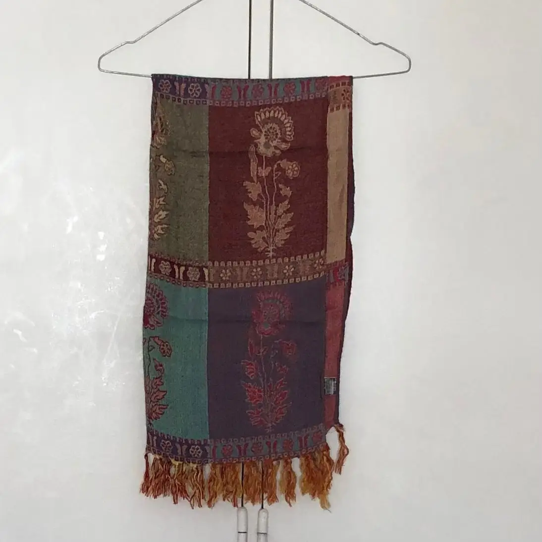 Bufanda de tela con diseño de bloques de colores y estampado floral. Ideal para complementar cualquier look con un toque bohemio y artesanal.