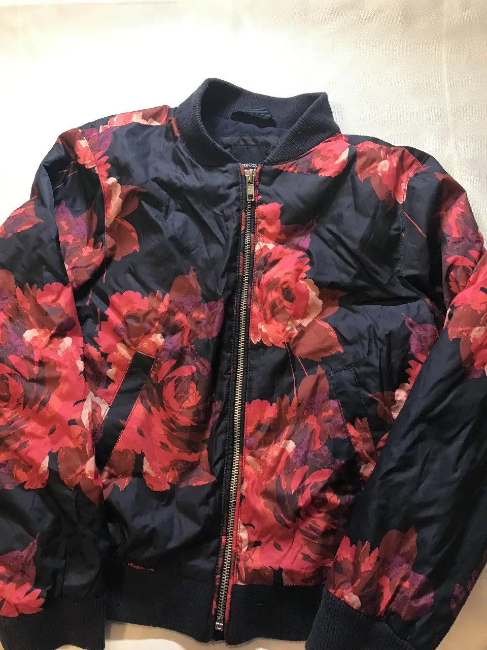 Campera bomber para niña con estampado floral en tonos rojos y azul marino. Ideal para un look casual y moderno. Cuenta con cierre y puños elastizados. Gap 10/11 años 