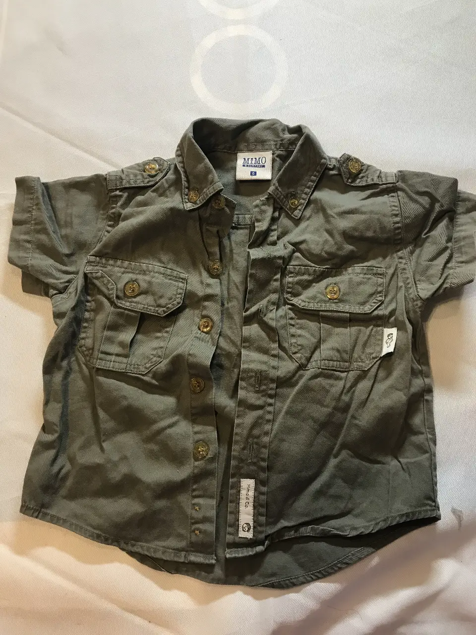 Camisa de niño manga corta, color verde militar, con dos bolsillos delanteros y detalles en los hombros. Marca MIMO A COMPANY, talle 0.