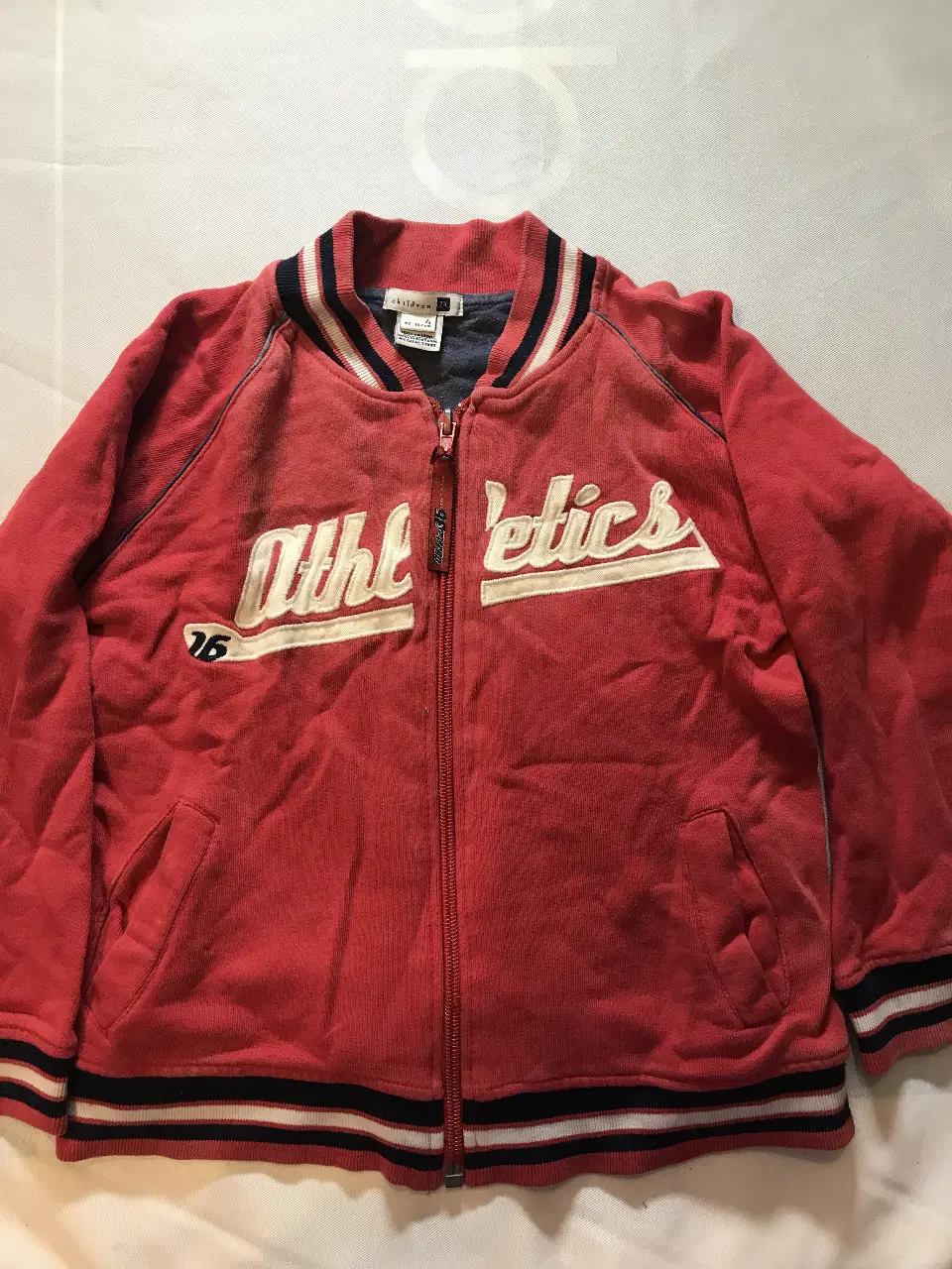 Campera deportiva roja para niño con cierre y detalles en blanco. Estampado "Athletics". Ideal para un look casual y cómodo. Zara 