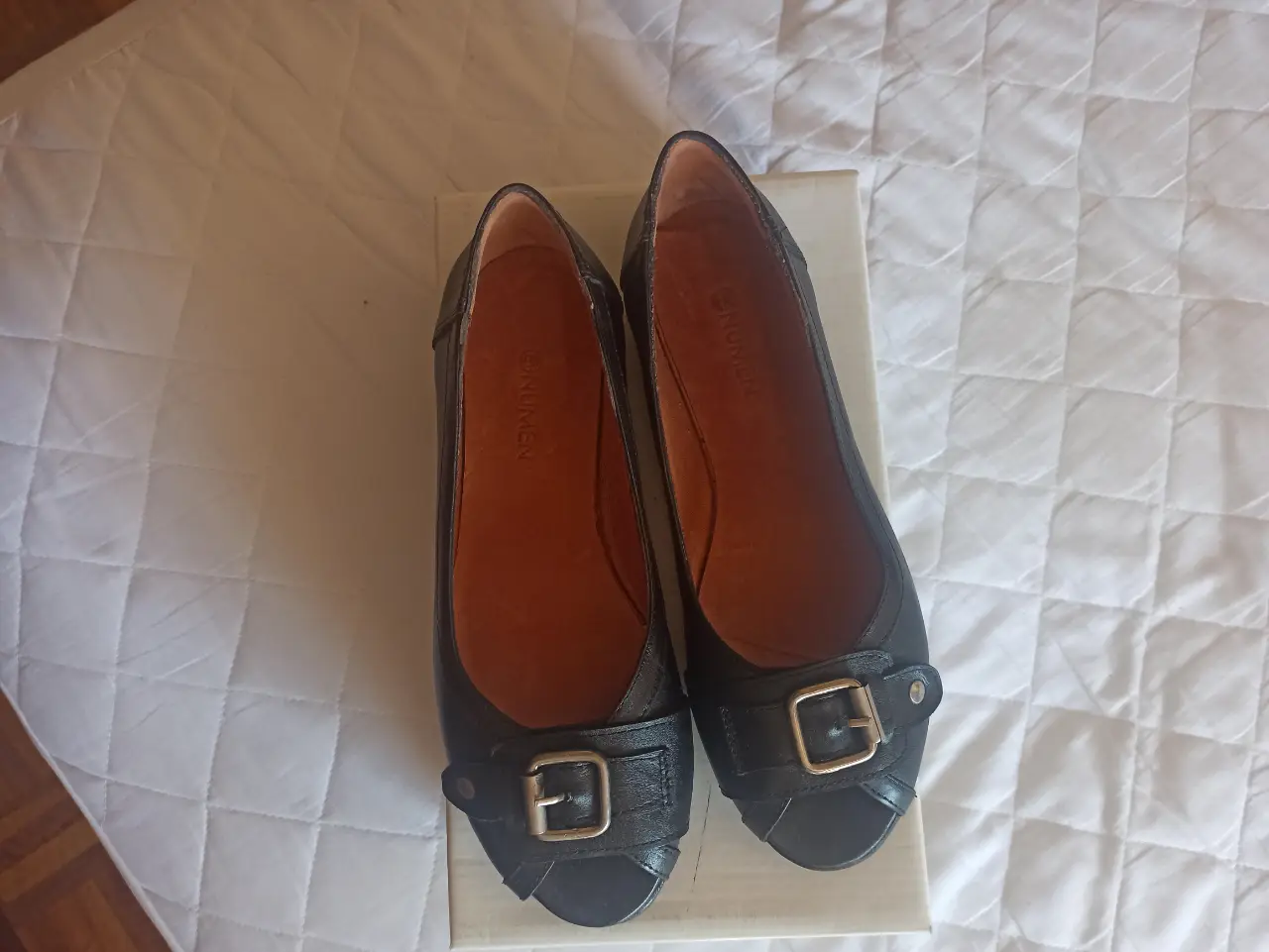 Ballerinas negras con hebilla dorada, ideales para un look elegante y cómodo. Perfectas para combinar con cualquier outfit.