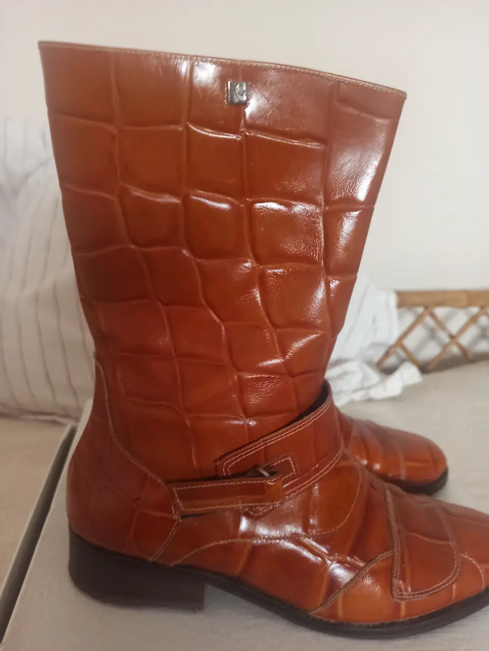 Botas de caña alta de cuero marrón con diseño tipo cocodrilo. Detalles de hebillas y costuras en color crema. Ideales para un look de invierno con estilo.