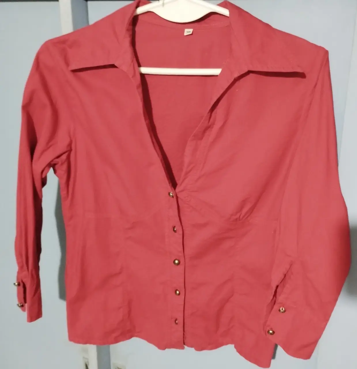 Camisa roja de mujer, lienzo elastizado, con botones dorados y cuello clásico. Tiene corte fruncido en el bajo busto. Ideal para un look elegante y versátil. Sisa 42 cm, largo total 50 CM, largo mangas (al codo) 42 cm.