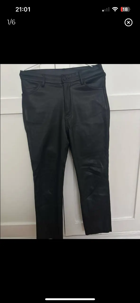 Pantalón de cuero sintético negro, tiro alto, corte recto. Ideal para un look moderno y sofisticado.