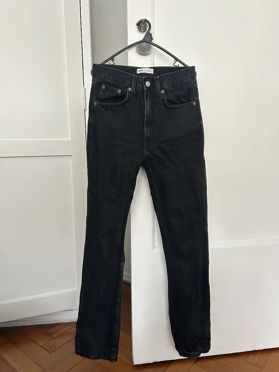 Jeans rectos negros de Zara, tiro medio, con bolsillos clásicos y etiqueta de la marca. Un básico atemporal para cualquier guardarropa.