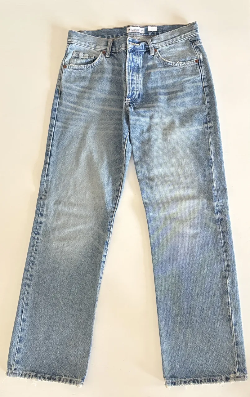 Jeans de tiro alto con roturas y detalles desgastados en la parte delantera. El bajo del pantalón es desflecado.