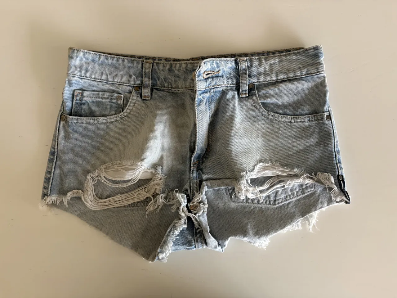 Shorts de jean tiro alto con roturas y detalles desflecados en los bordes.