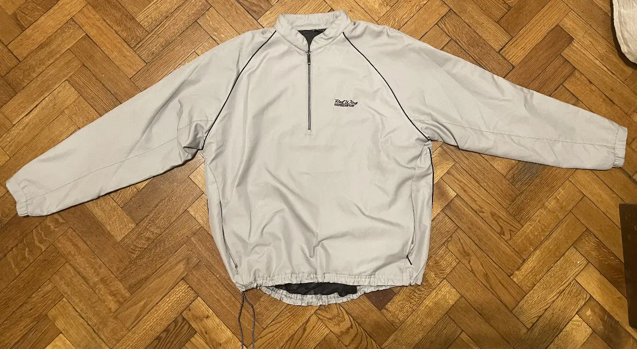 Campera deportiva / rompevientos gris con cierre y cuello alto. Ideal para actividades al aire libre o uso casual. Con logo de la marca en el pecho.
