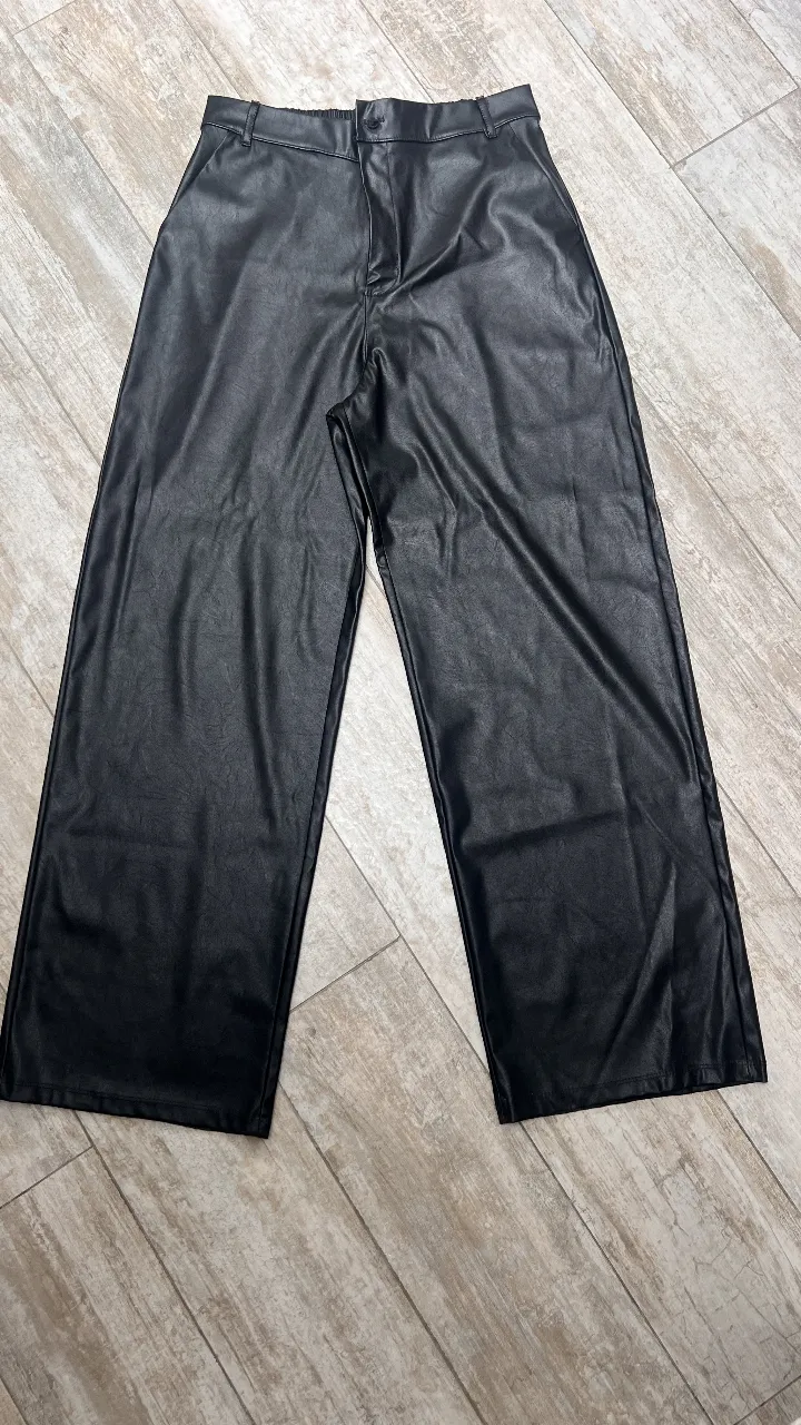 Pantalón sastrero de cuero sintético negro, tiro alto y corte ancho. Ideal para un look moderno y sofisticado.