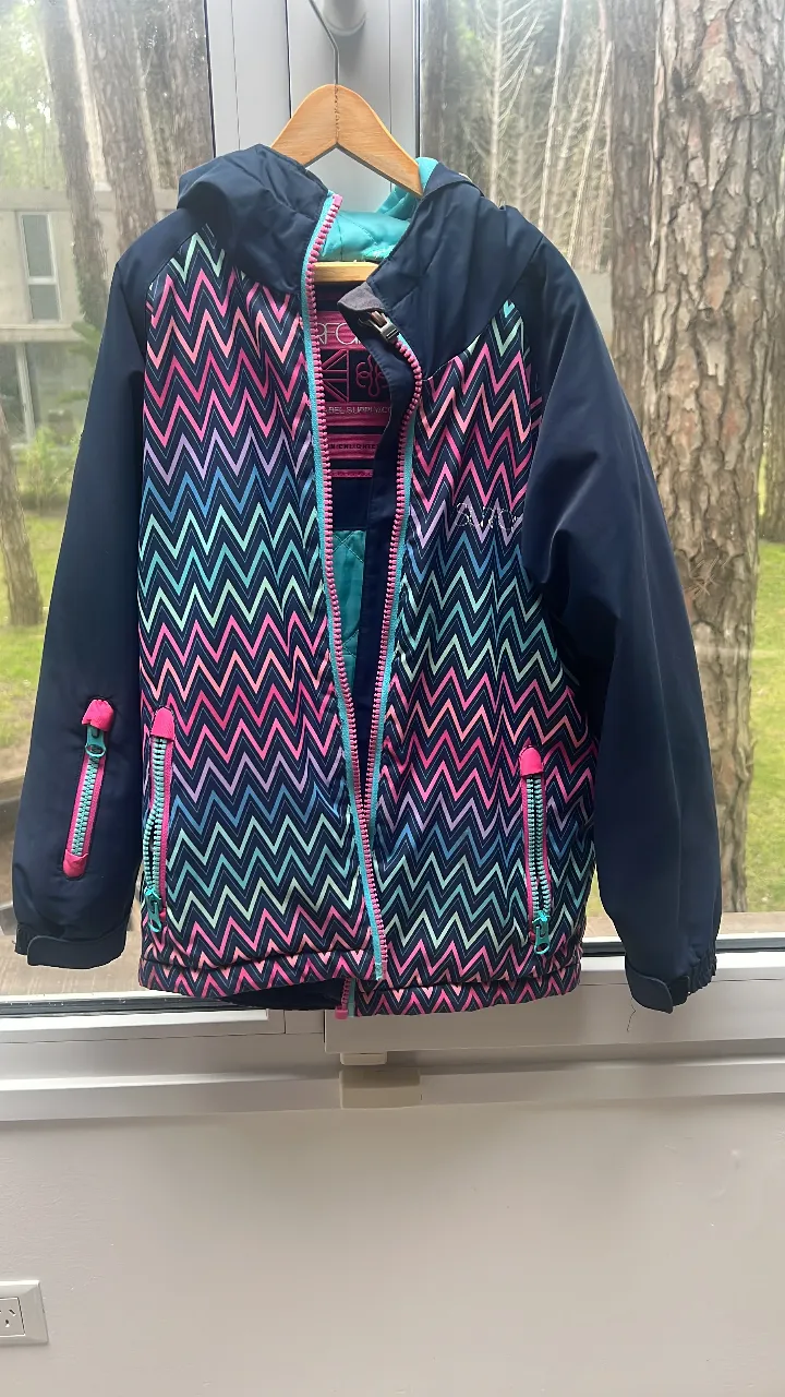 Campera de abrigo para niña, con diseño de zig-zag en tonos rosa, turquesa y negro. Posee cierre frontal y bolsillos con cierre. Ideal para actividades de invierno.