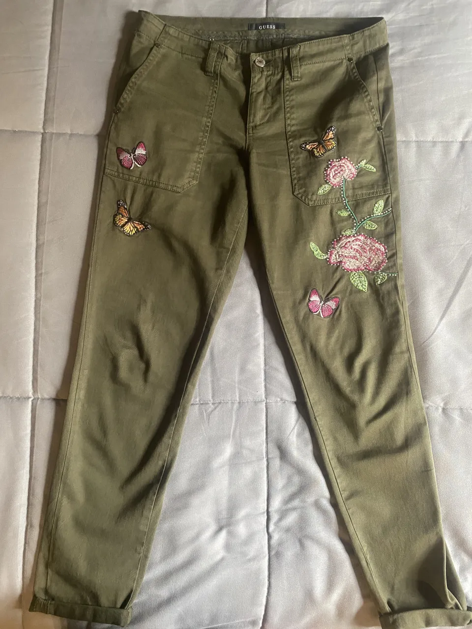 Pantalón  color verde militar con bordados de mariposas y flores. Marca Guess. Talle 26. Original