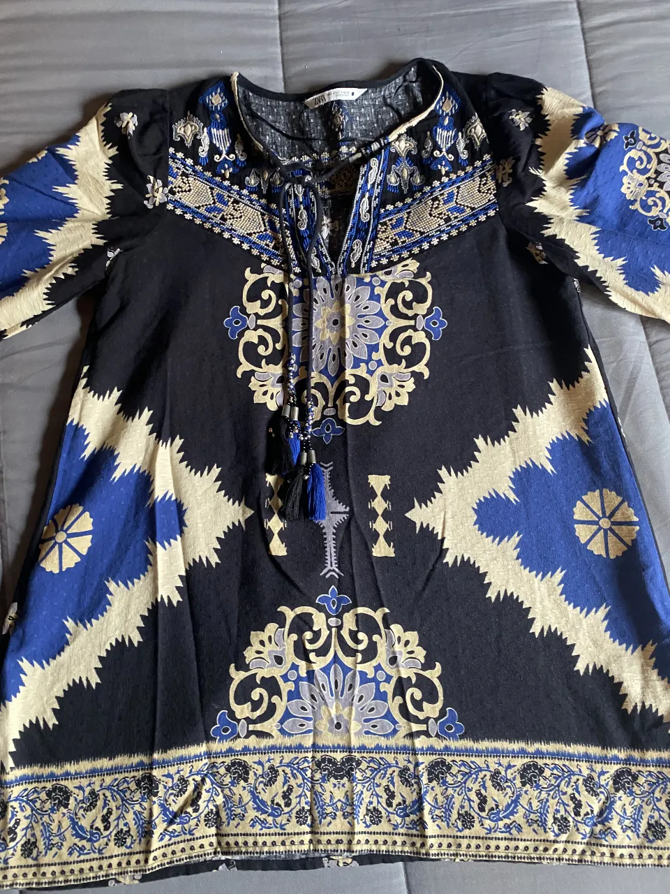 Vestido estampada con detalles bordados y flecos. Posee escote con cordones y mangas largas con puño. Ideal para un look boho chic. Talle S pero amplio. De India.