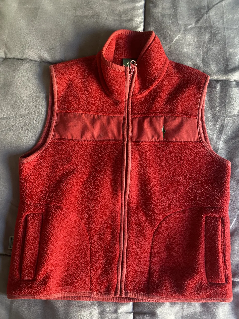 Chaleco de polar rojo, ideal para abrigarse en días frescos. Posee un detalle bordado de cactus en el frente y bolsillos laterales.