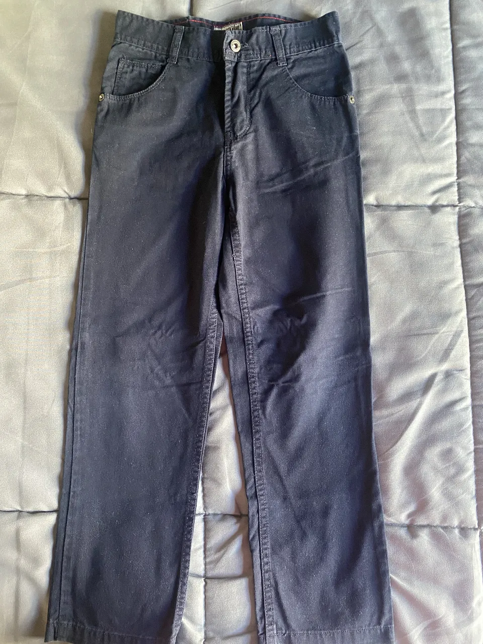 Pantalón de gabardina azul marino, ideal para el día a día. Posee bolsillos delanteros y traseros, y un cierre con botón.