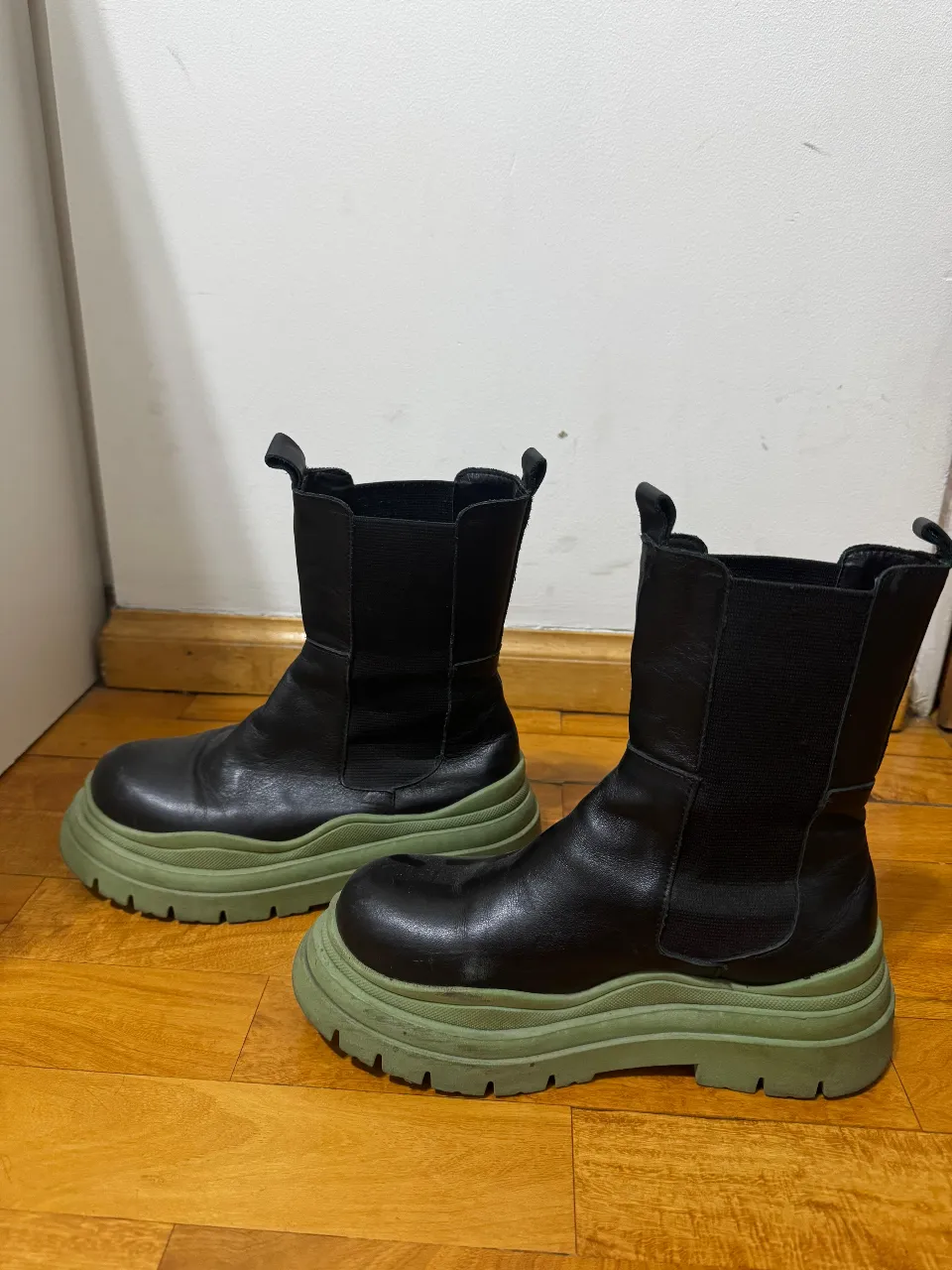 Botas negras con suela verde. Diseño moderno y urbano, ideales para un look casual y con estilo.
