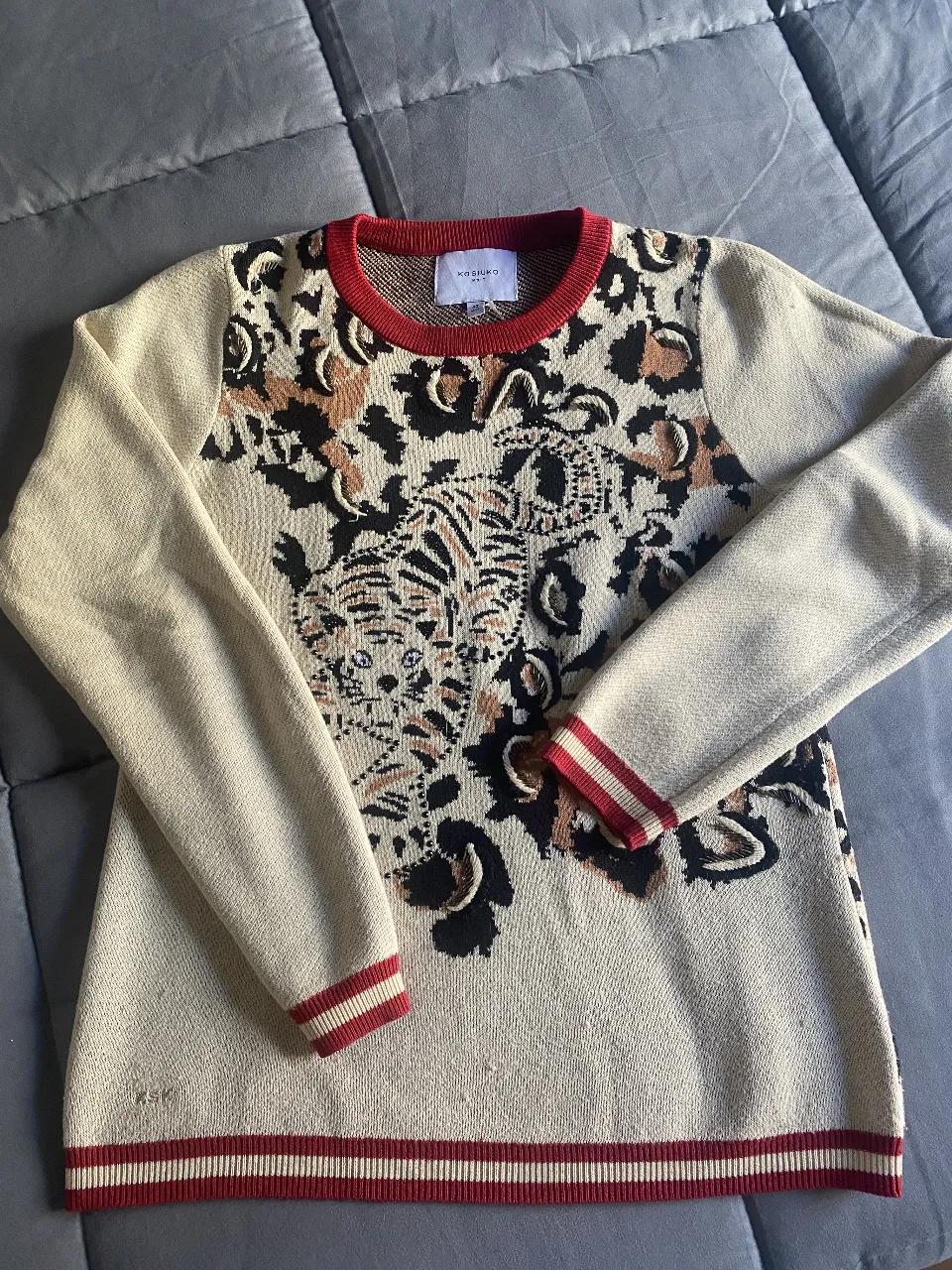 Sweater de mujer con estampado de tigre, con brillitos delicados y detalles de leopardo. Cuello, puños y cintura en color rojo. Talle M. 