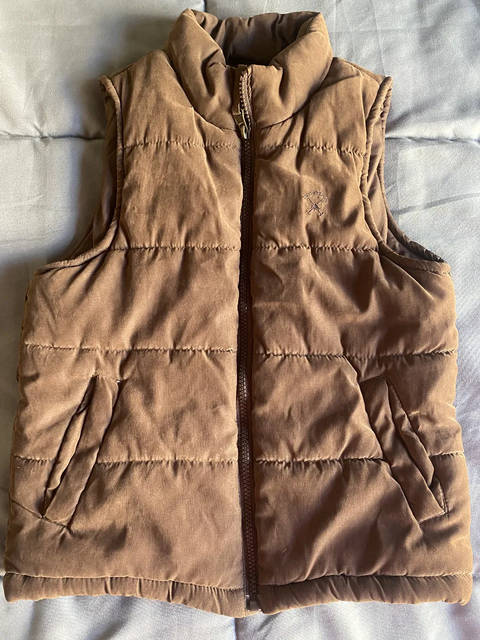 Chaleco acolchado de la marca KEVINGSTON, ideal para los días frescos. Su diseño clásico y color marrón lo hacen súper versátil para combinar con cualquier outfit. Perfecto para un look casual y cómodo.