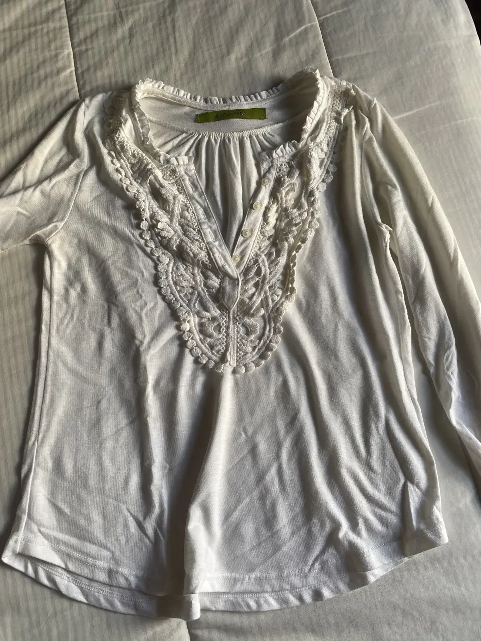 Blusa blanca con detalles de encaje en el cuello y botones. Ideal para un look elegante y femenino.
