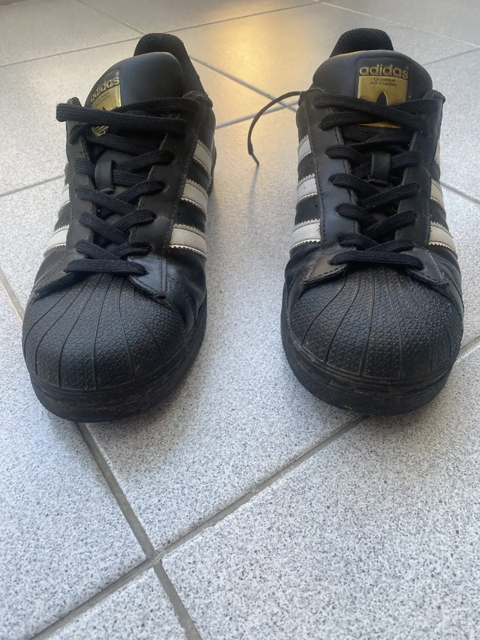 Zapatillas Adidas Superstar negras con detalles blancos. Clásicas y cómodas, ideales para un look casual y urbano. Unisex