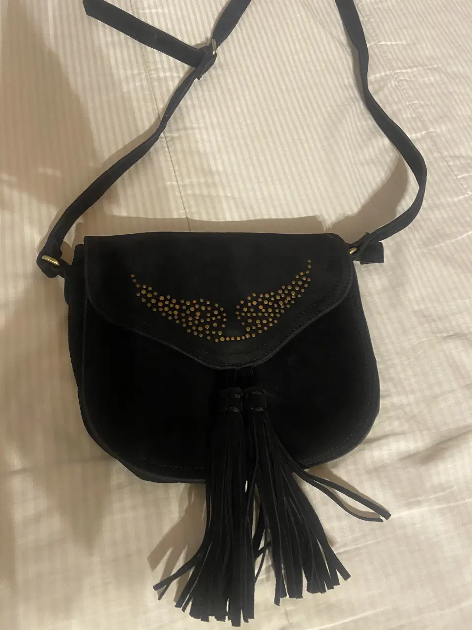 Bandolera negra de gamuza con detalles dorados y flecos. Ideal para un look casual y canchero.