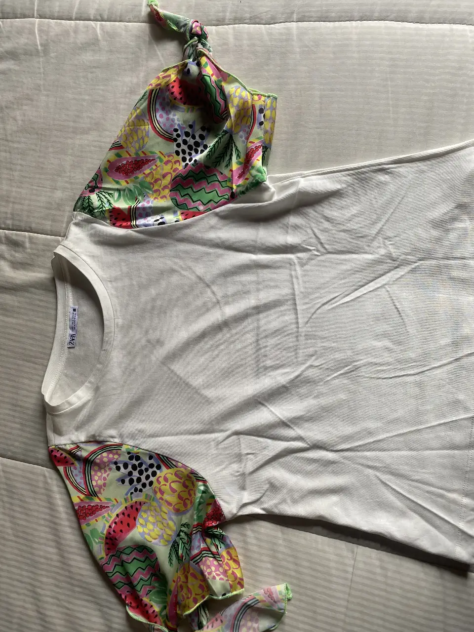 Remera blanca Zara de manga corta con mangas estampadas con motivos frutales. Cuello redondo y talle S.