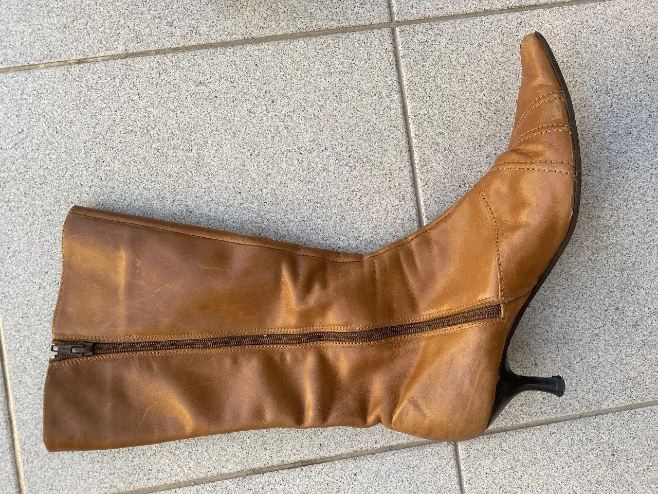 Botas de caña alta de cuero marrón con taco fino. Diseño elegante y atemporal, ideal para complementar cualquier look.