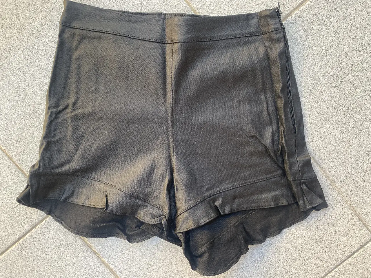 Short de jean negro con detalles de roturas y flecos en el borde inferior. Ideal para un look casual y moderno. 