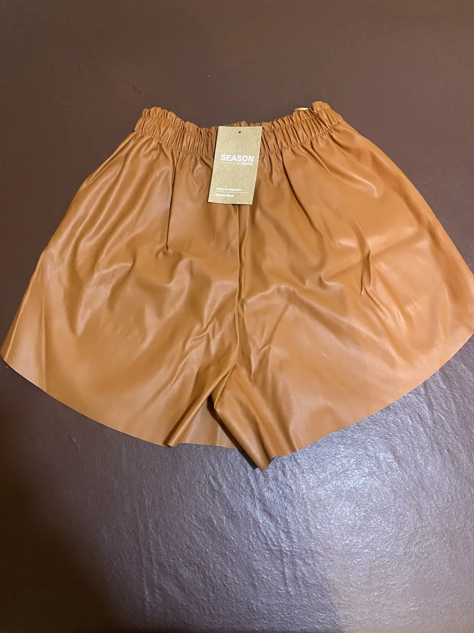 Short de cuero sintético color marrón, tiro alto, con cintura elastizada. Ideal para un look moderno y canchero.