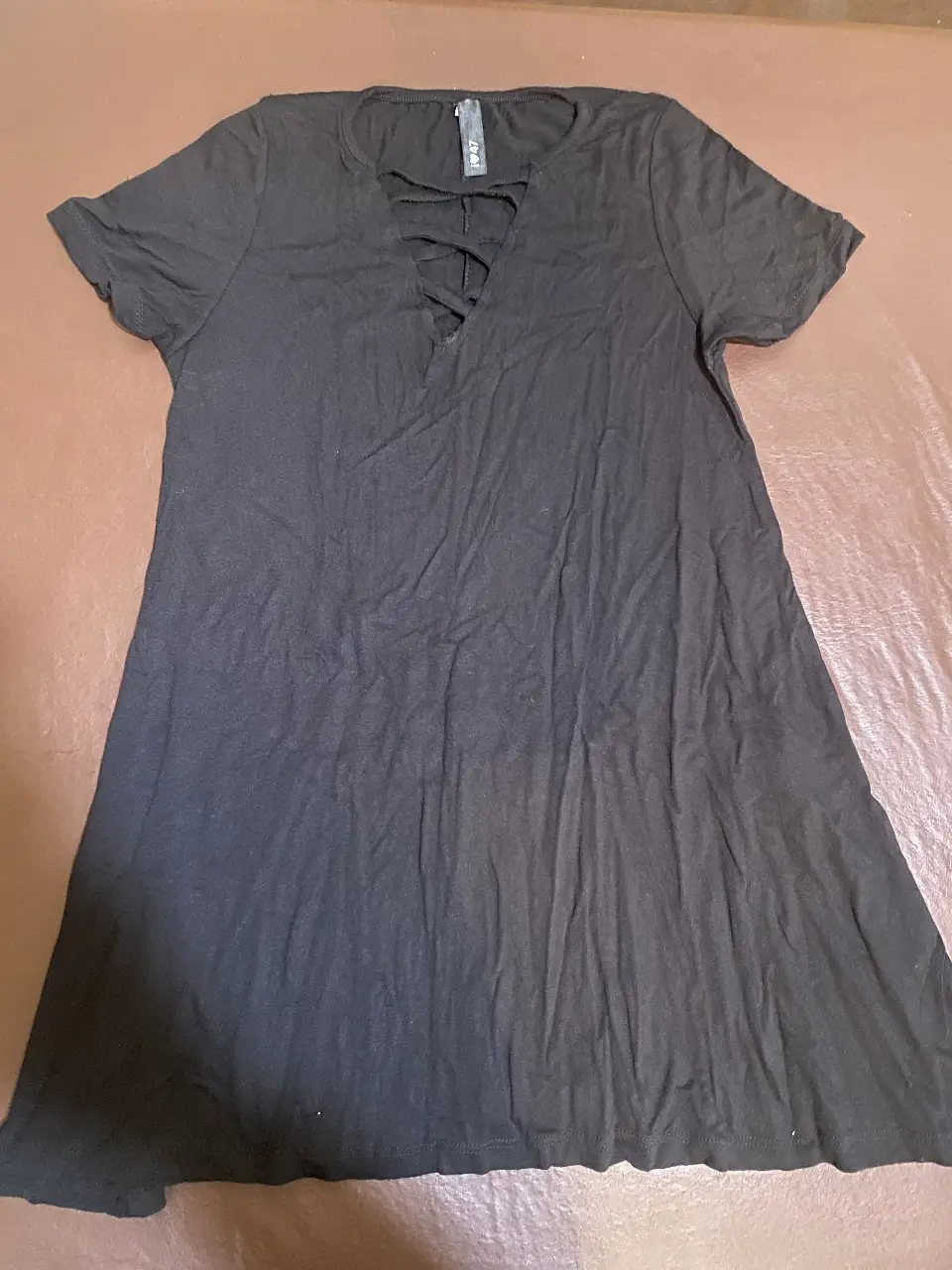 Vestido negro corto con escote en V y detalle de cordones. Ideal para una salida casual o una fiesta.