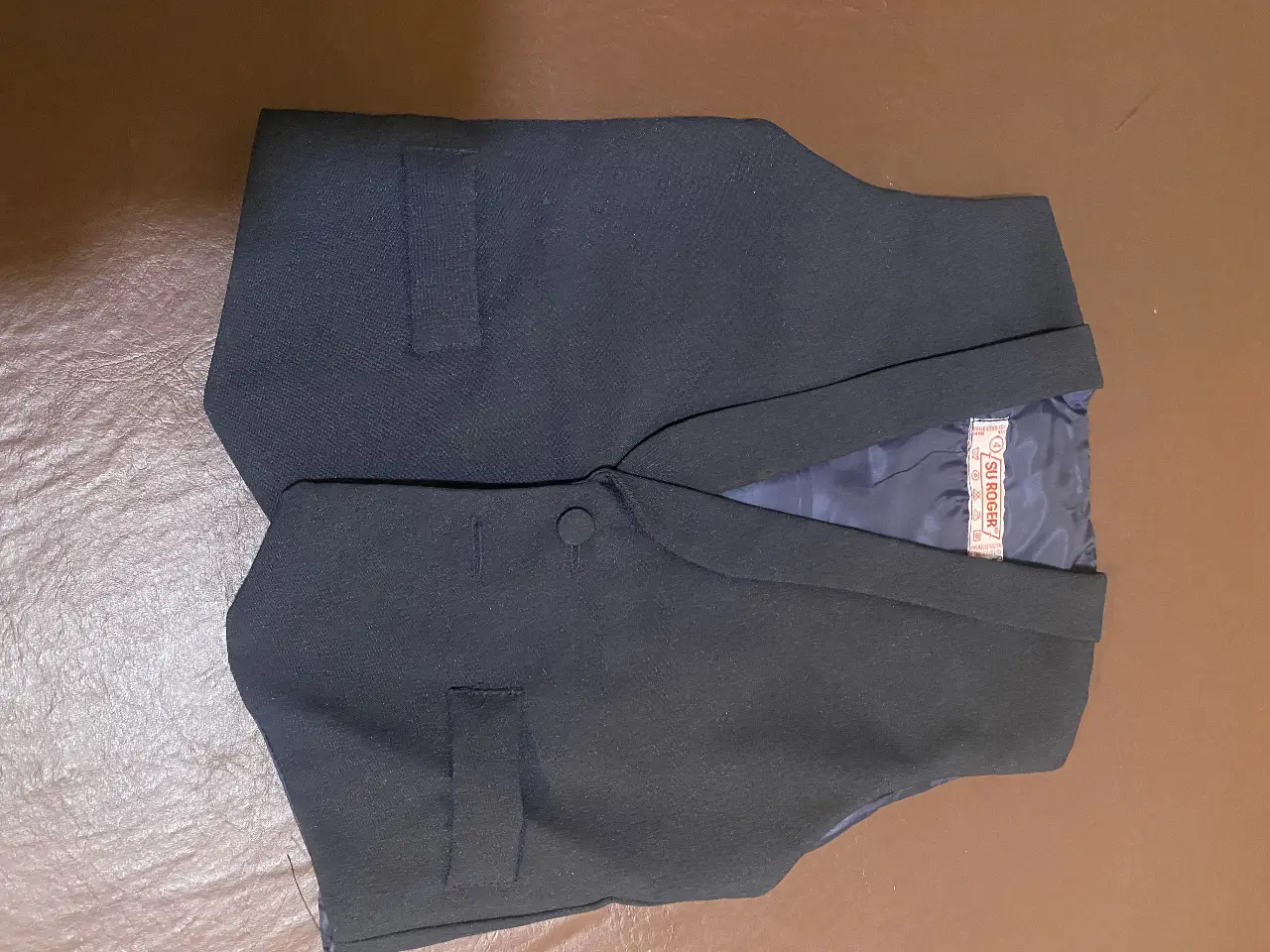 Chaleco de vestir azul marino para niño, con dos bolsillos delanteros y un botón para cerrar. Ideal para eventos formales o para completar un look elegante.